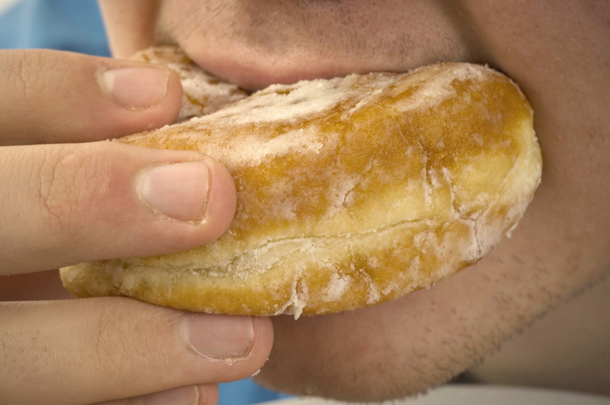Close-up of man eating jam donut.