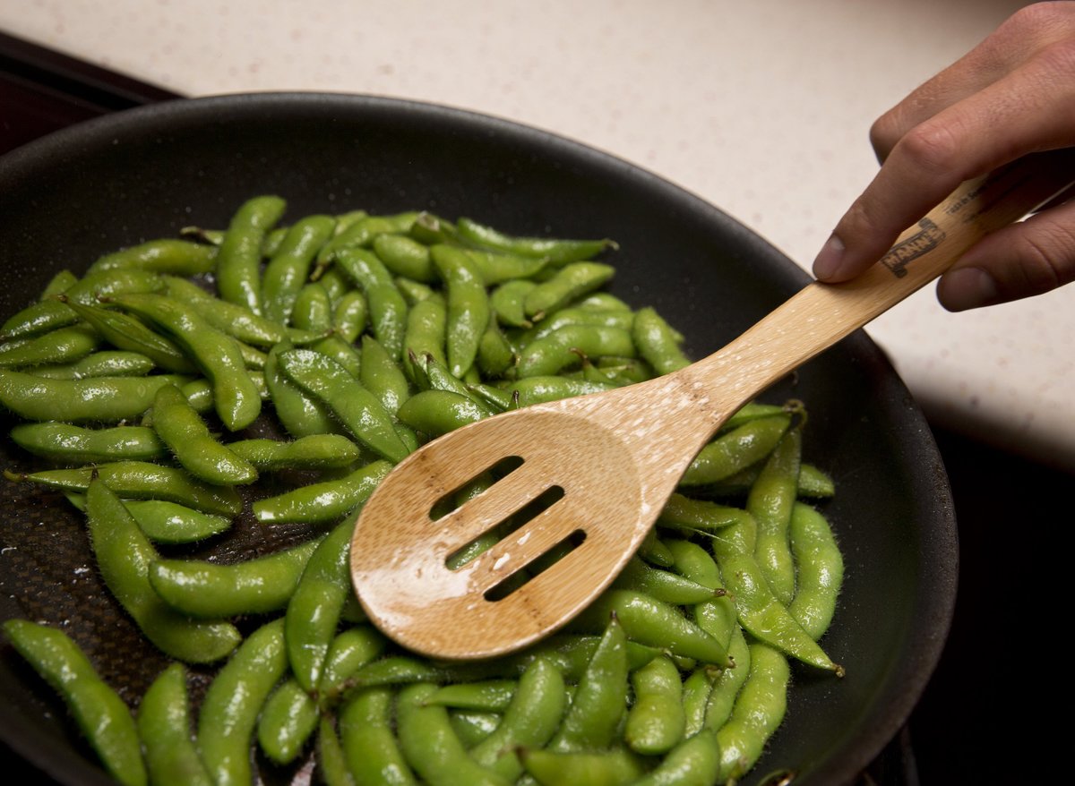 Farmer cooks edamame in a pan.