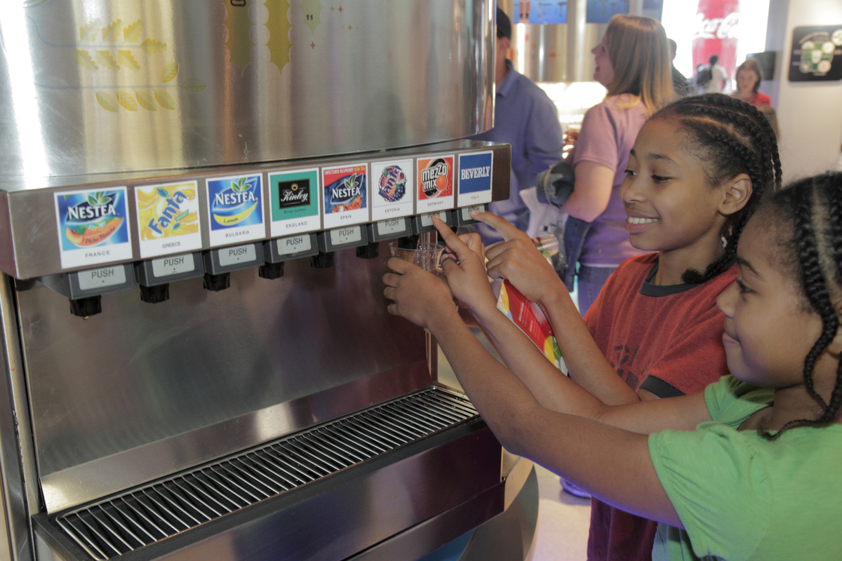 Two girls pour soda at the 'Taste It!' exhibit in the World of Coca-Cola.
