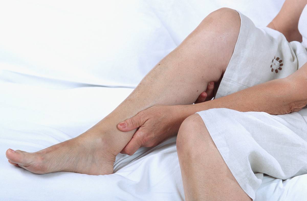 An elderly woman clutches her sore ankle.