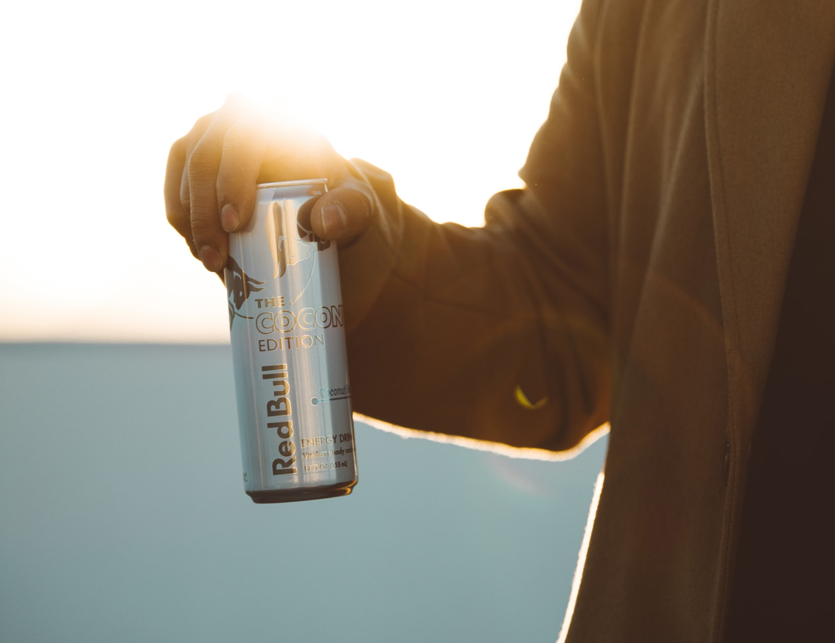 A man holds a can of Red Bull against the sunlight.