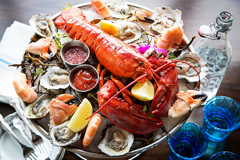 lobster on a platter with oysters, shrimp, and dipping sauces