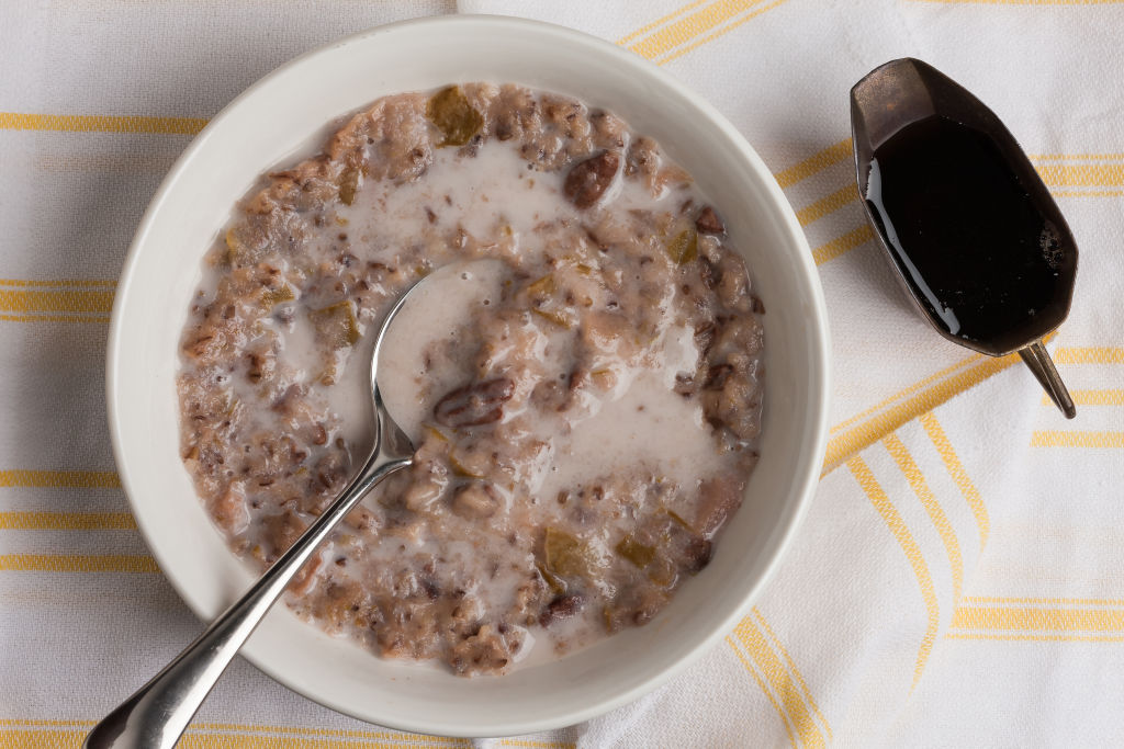 oatmeal in a bowl with a spoon and a side of maple syrup