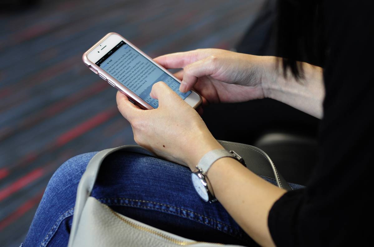 A woman texts someone while waiting at an airport.