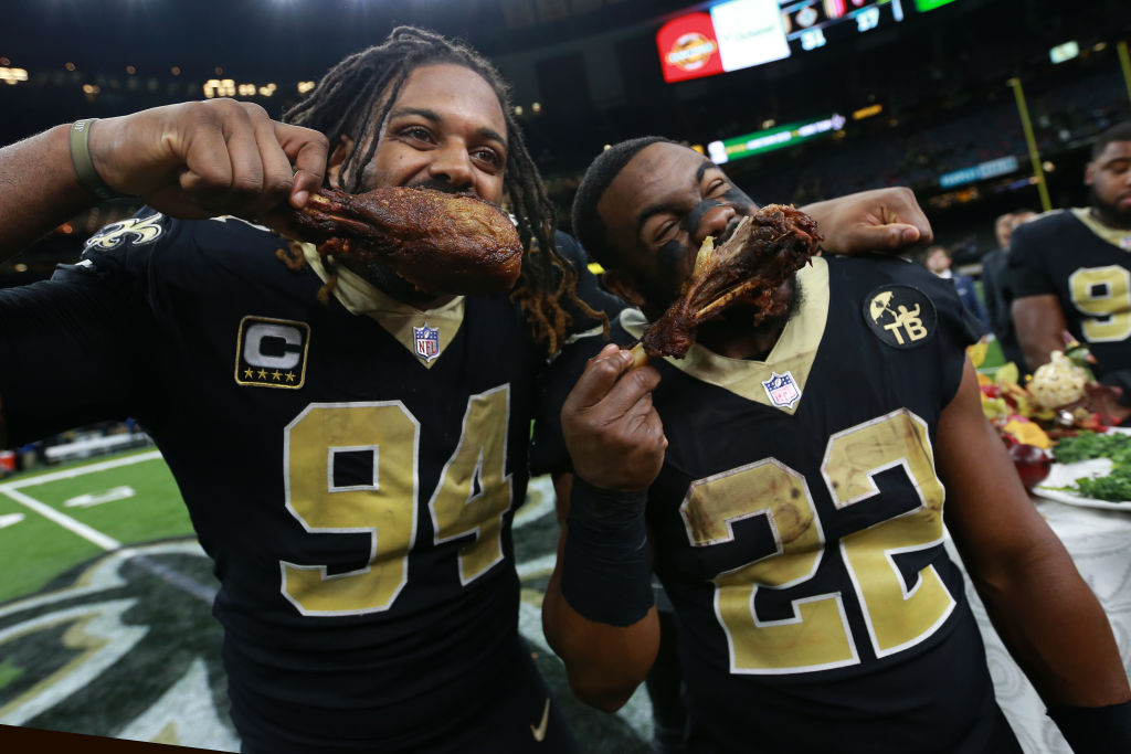 cameron jordan and mark ingram eating turkey legs on a football field