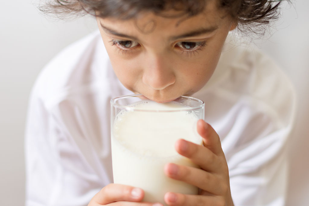 a young boy drinking a glass of milk